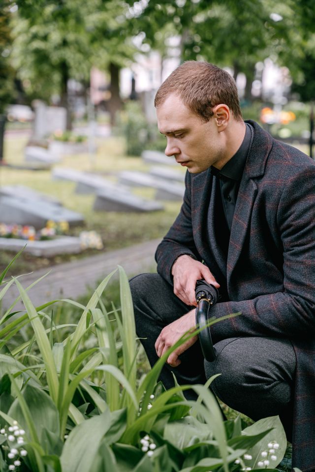 Un homme recueilli, agenouillé au cimetière en mémoire d'un proche